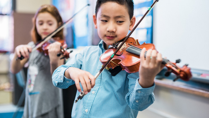 Photo of two kids taking violin lessons