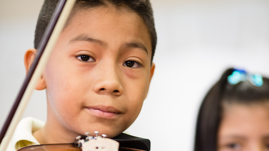 Student plays the violin during a school music program.