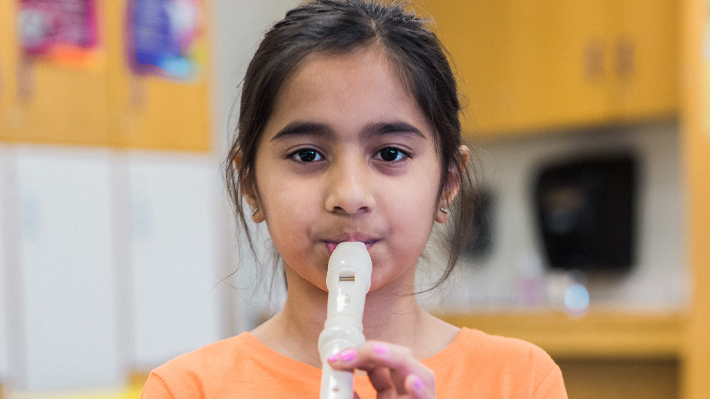 Student plays a recorder during a classroom music lesson.